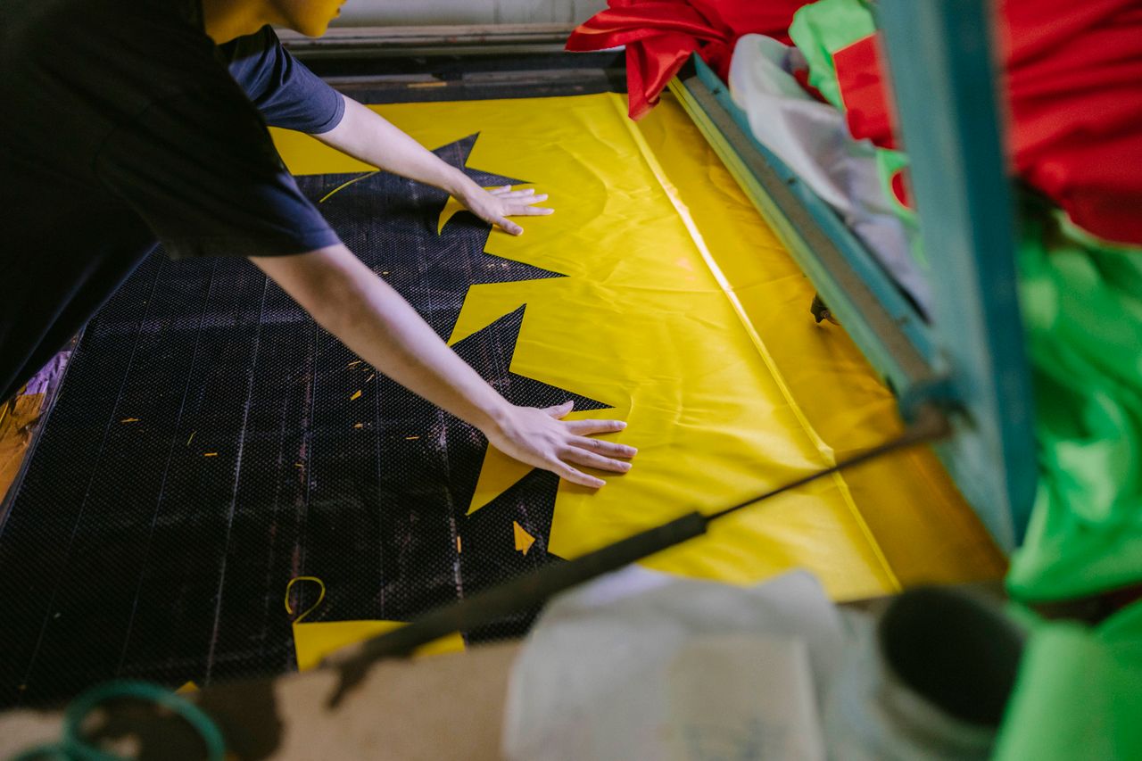 services-02 A person laying out bright fabric in a workshop setting.