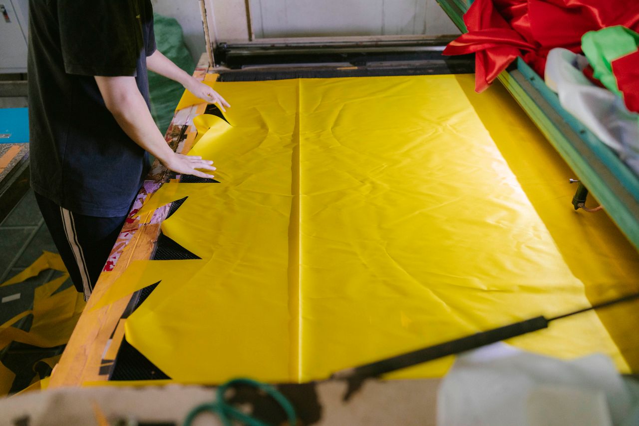 Crafting Captivating Headlines: Your awesome post title goes here A person cutting yellow fabric for textile production in a workshop.