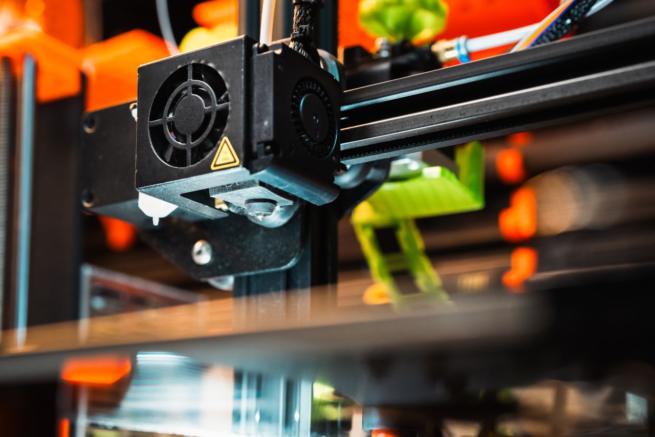 services-01 Detailed view of a 3D printer nozzle working in a modern manufacturing setting.